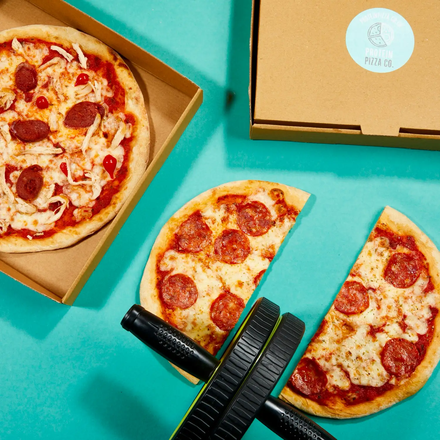 Protein Pizza Co. pizzas on a teal background beside a foam roller