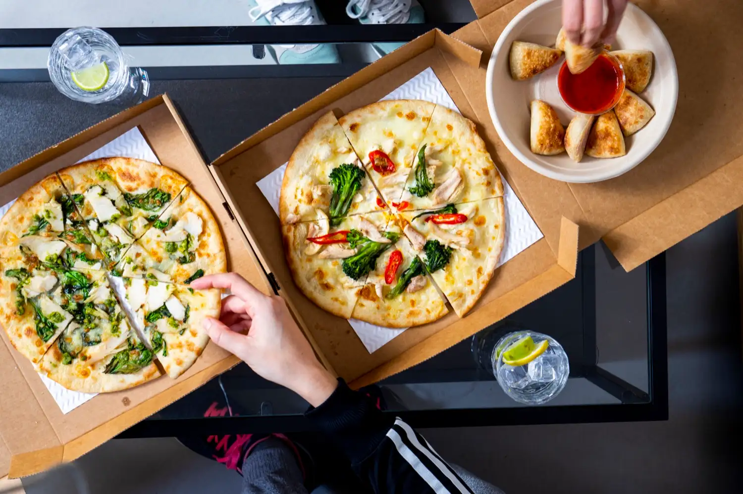 Two pizzas and a bowl of dough balls shared across a table